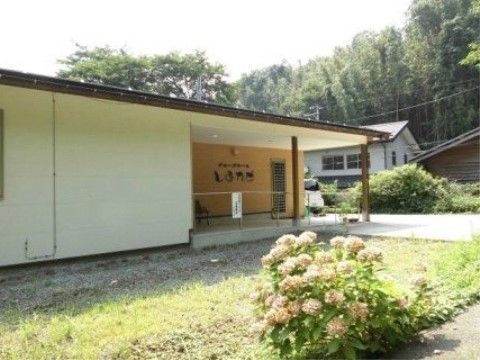 入口に軒下のスペースがあり、ベンチが置かれている。玄関までは緩やかなスロープがあり、手すりが取り付けられている。