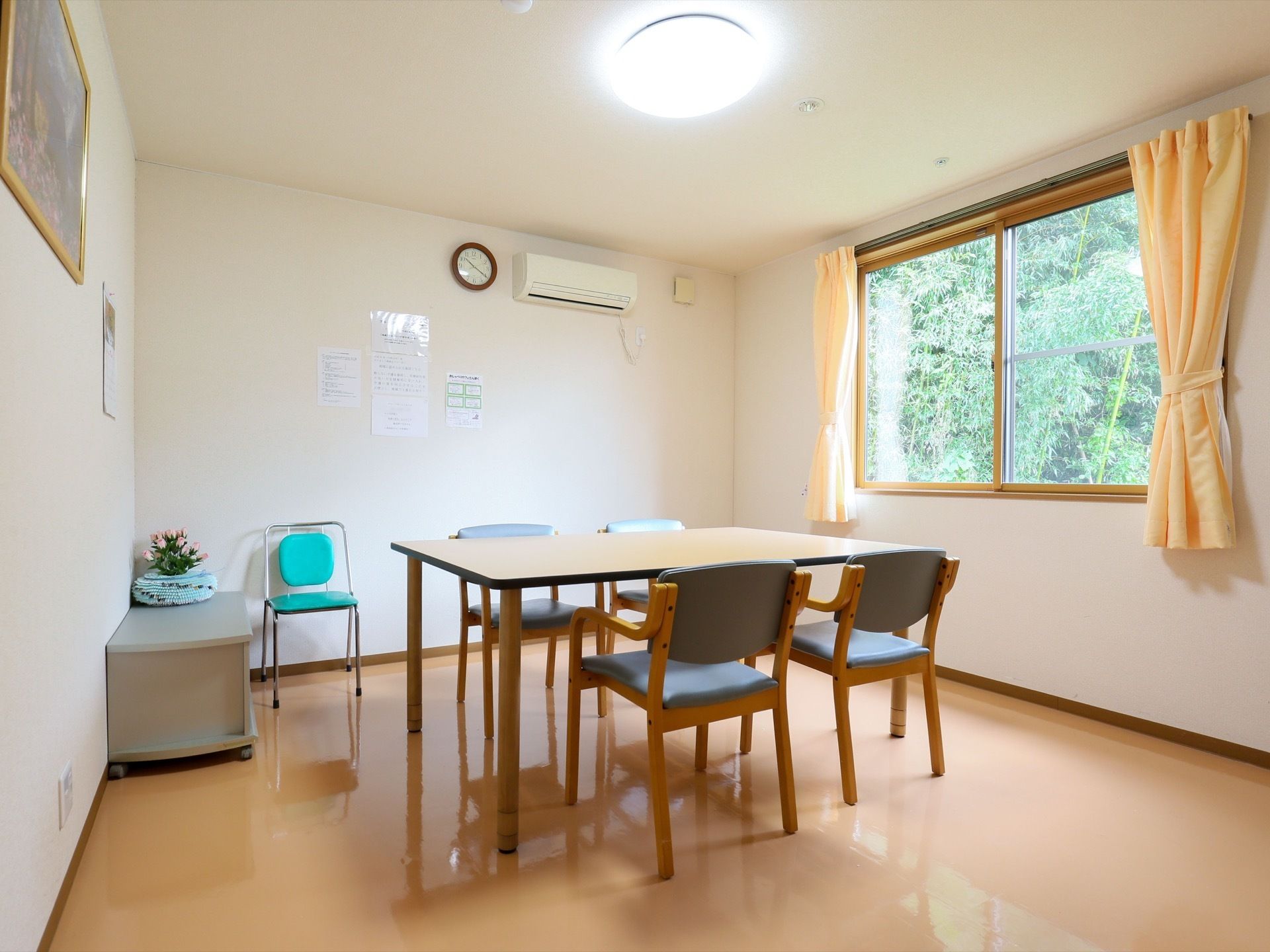 館内に個室の談話室を用意しています。テーブルが中央にあり、その周りに椅子が４脚並んでいる。右手に窓が開いている。