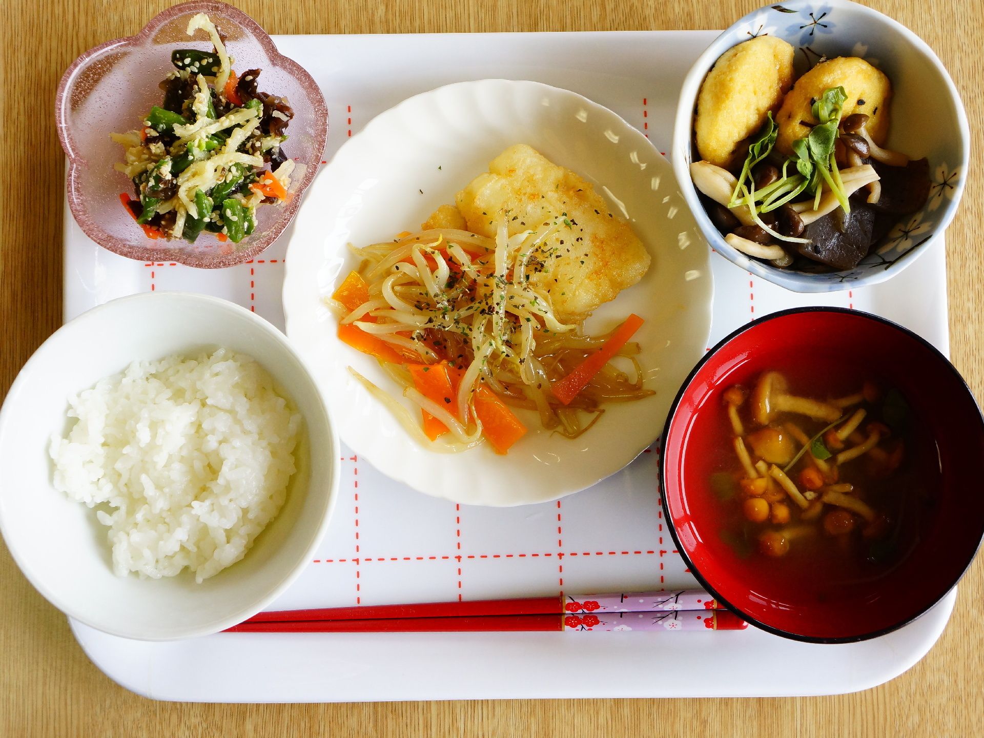 がんもどきと野菜の含め煮や青菜の和え物、なめこの味噌汁等、野菜を中心をした健康的な食事が配膳されている。