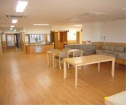 木目調のフローリングの壁際にソファを並べ、傍にテーブルセットを配置している。火災報知器を設置し、防災設備も整えている。