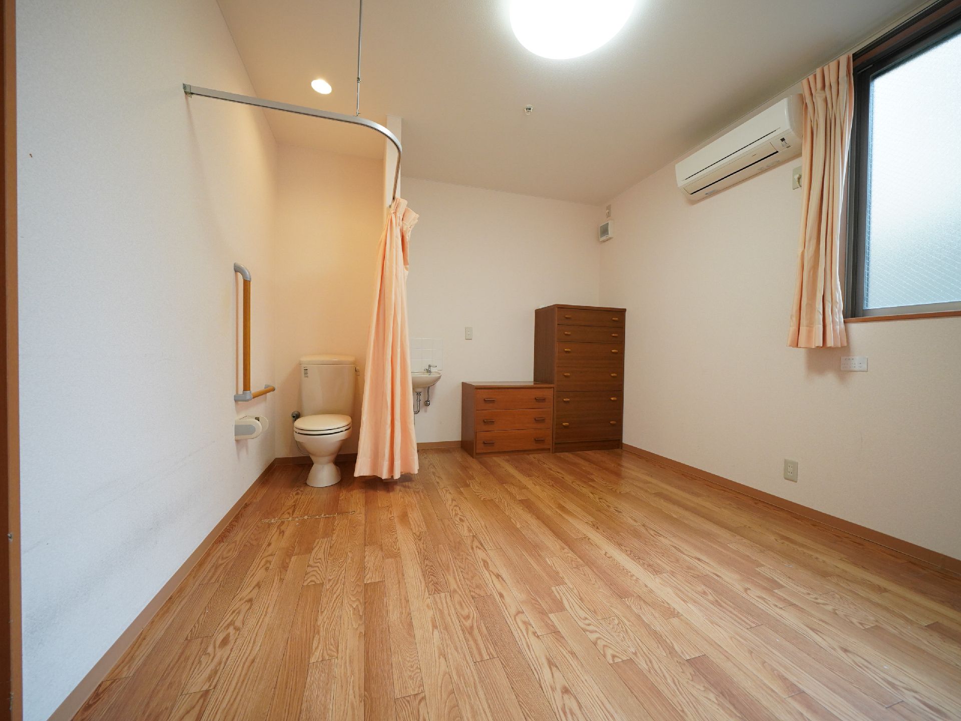 カーテンで仕切られたトイレと、小さな洗面ボウルのある個室