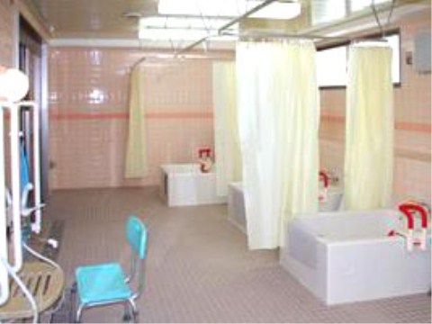 赤い手すりがついた浴槽が３つあり、それぞれシャワーカーテンで区切られている。洗い場に水色のシャワー椅子が置いてある。