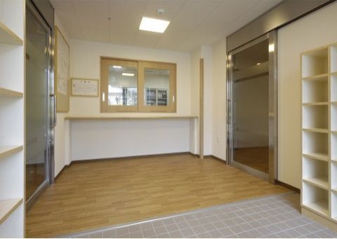 玄関のたたきの両側には白い靴箱が設置されている。館内へ入る部分はバリアフリーになっており、フローリングの床になっている。