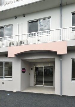 玄関は少し奥まった部分にあり、雨の日でも濡れずに出入りができる。ベランダには柵が付いており、エアコンの室外機が置かれている。