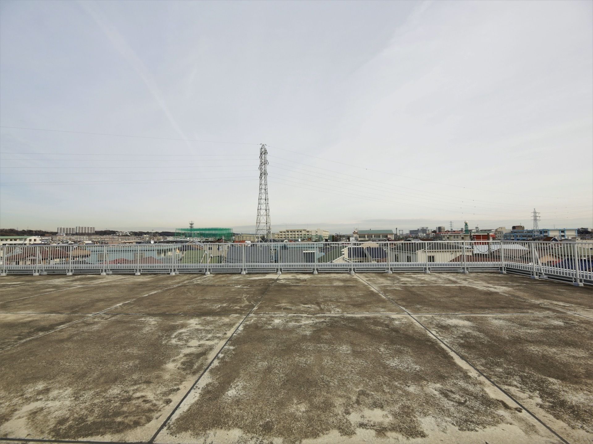 コンクリート張りで広いスペースの屋上からは、周りの景色が良く見える。住宅街で高い建物がなく、遠くの山まで見える。