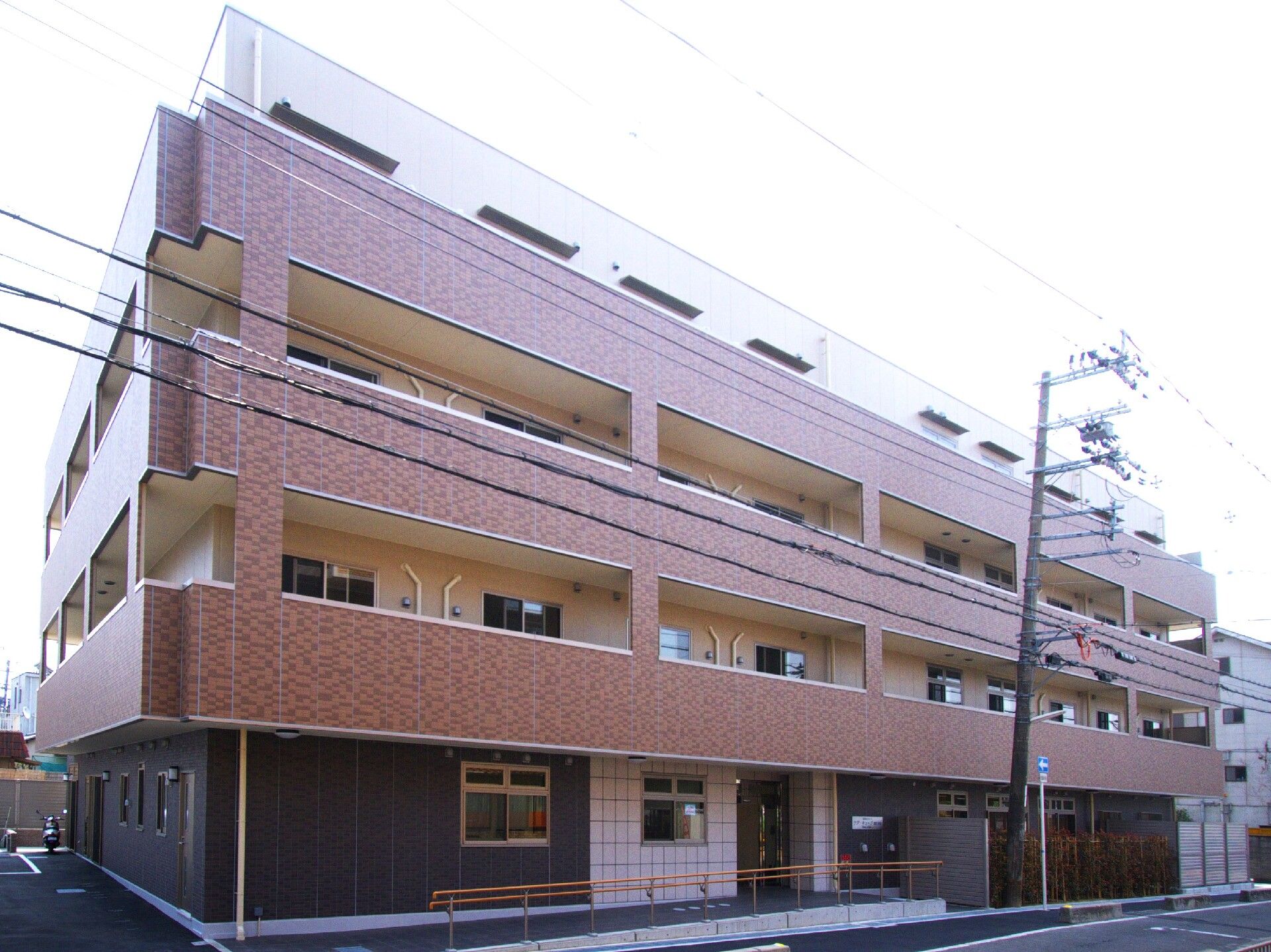 施設外観は赤茶色のレンガの外壁、３階建てで入り口にはスロープがついている