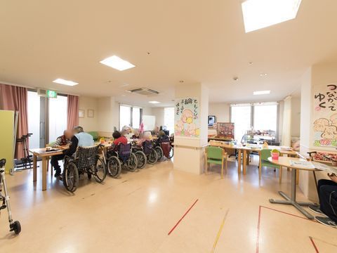 車椅子に座った入居者の方たちがテーブルについている、広い食堂