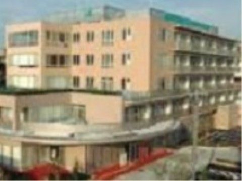 病院の建物の外観である。建物は５階建てで、外壁の色はベージュ基調になっている。建物の屋上に病院名が表示されている。