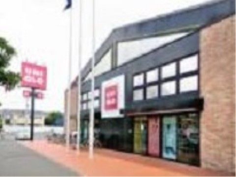 衣料品店の店舗の外観である。建物の入口には屋根が設置され、店舗の前には旗を立てるポールが建てられている。