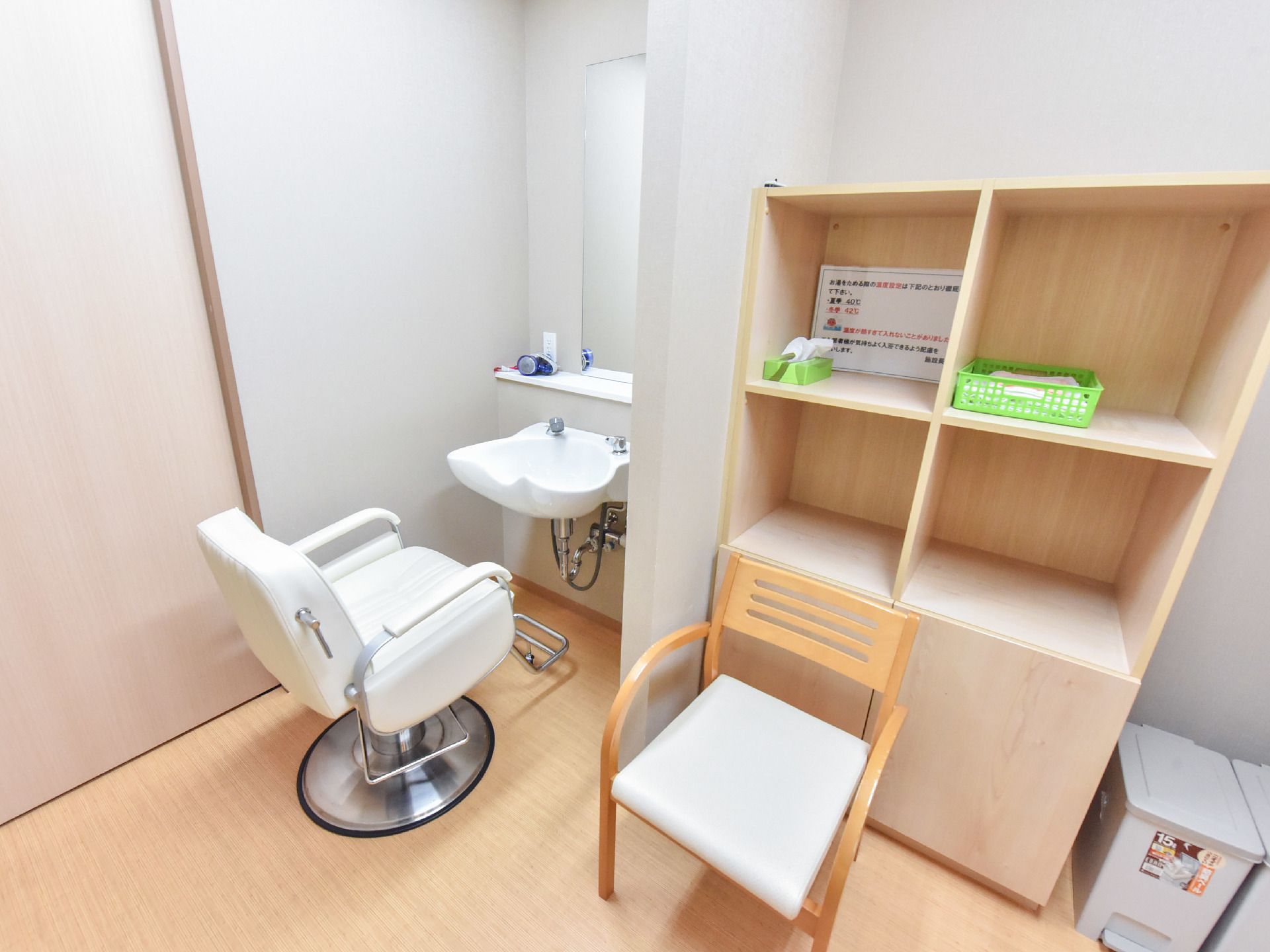 床や棚などが木目調でとても落ち着いている。洗面台の前には理髪用の椅子がある。横には大きな戸棚があり、タオルなどが収納できる。