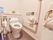 車椅子に対応した洋式トイレには、左右ともにペーパーホルダーと手すりが設置されている。左手の壁に呼び出しボタンとトイレを操作するボタンがある。