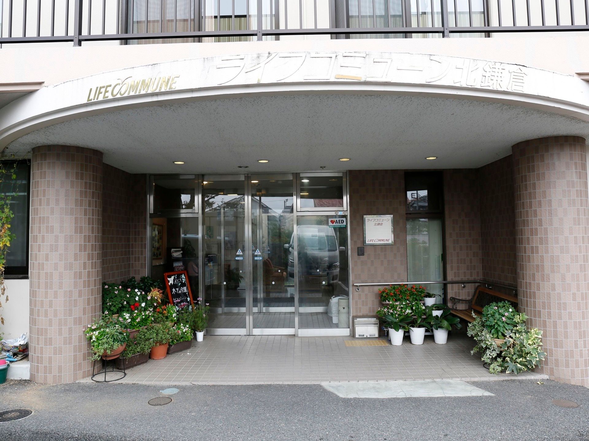 玄関は大きなガラス張りの自動ドアになっている。ベンチ、その周辺にたくさんのプランターが置かれている。段差のない入口となっている。