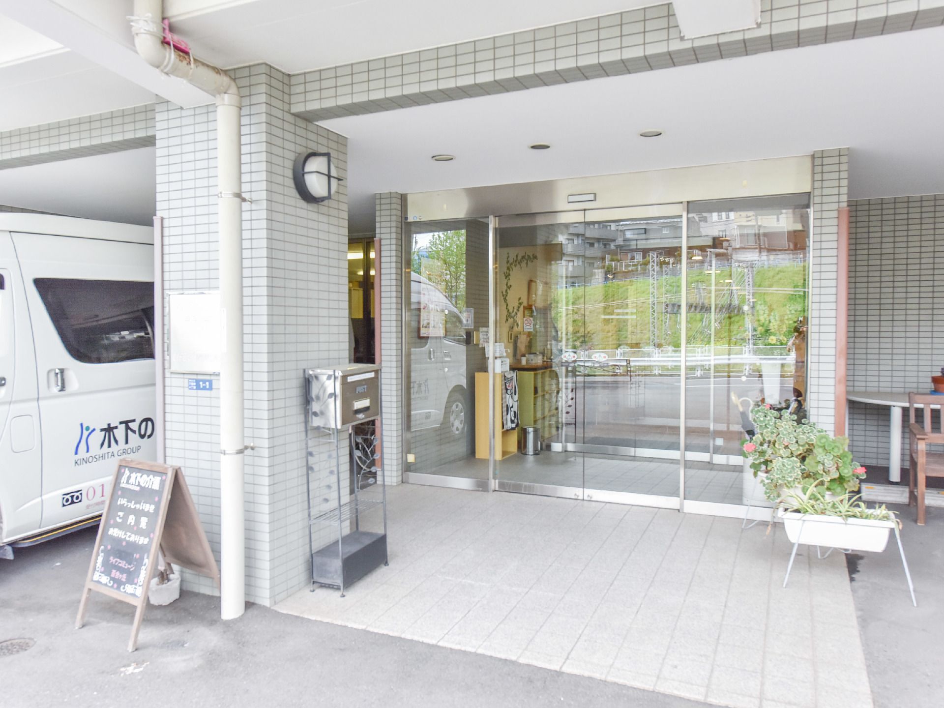 施設へと入るエントランスには、自動ドアを設置している。また玄関先にはブラックボードや郵便受けが置かれている。