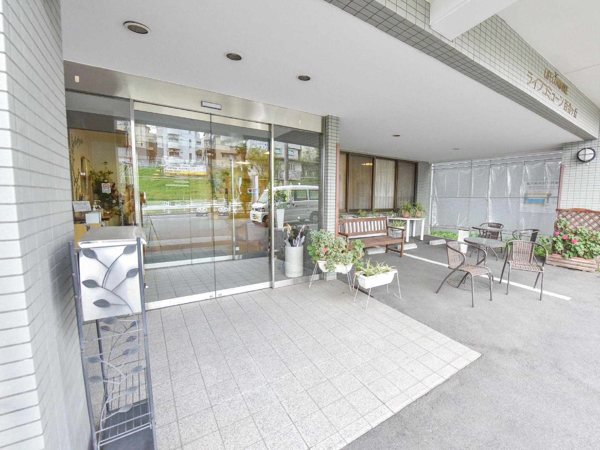 エントランスでは、プランターに入った草花が入居者を出迎えている。また入り口には風除室があり、傘立てが置かれている。