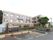 L字型の建物が建っている。1階部分はフェンスと植え込みで囲まれていて、目隠しされた状態になっている。