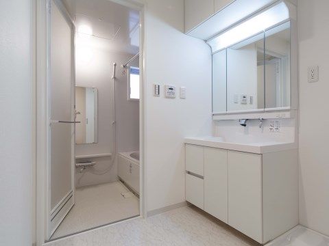 白い壁、白い床が美しい収納付き洗面所と、段差なく続く浴室