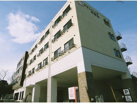 1階部分に駐車スペースがある、白とベージュ系の4階建ての施設