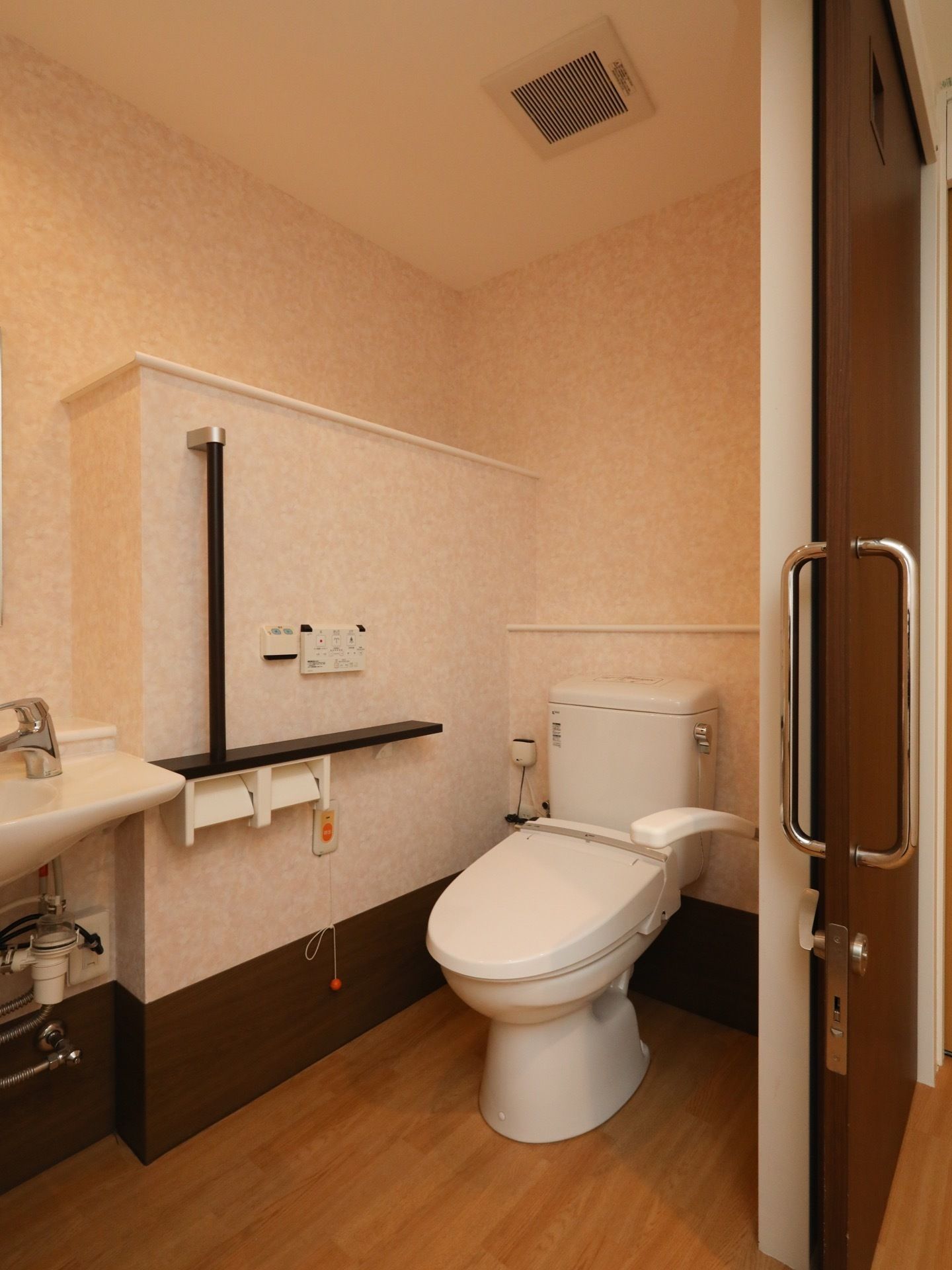 引き戸で仕切られた洋式トイレがある。両側の壁には手すりが備え付けられており、ナースコールも設置されている。