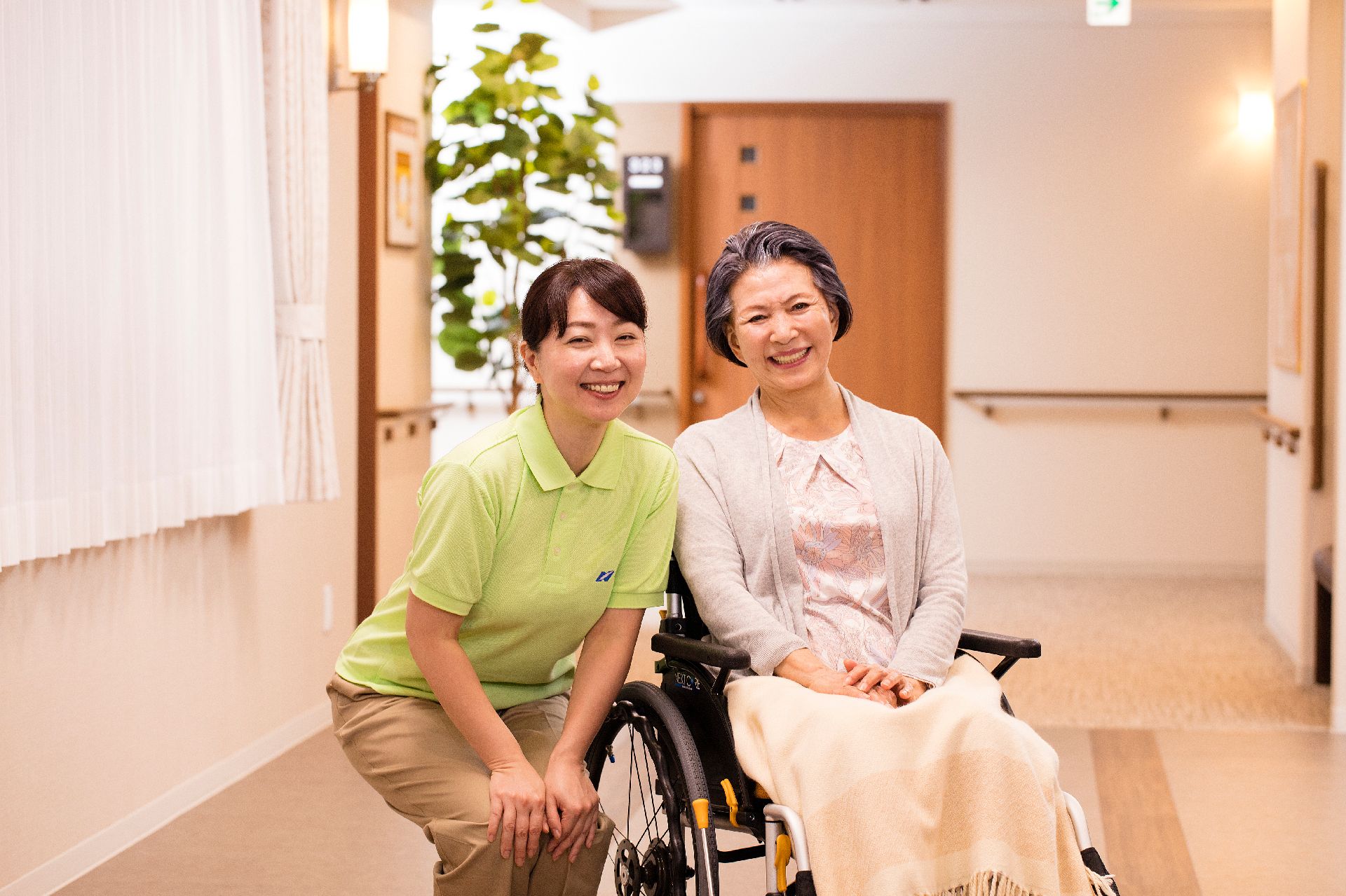 ベッドに横になっている入居者の脈をとる医療従事者と横についているスタッフ