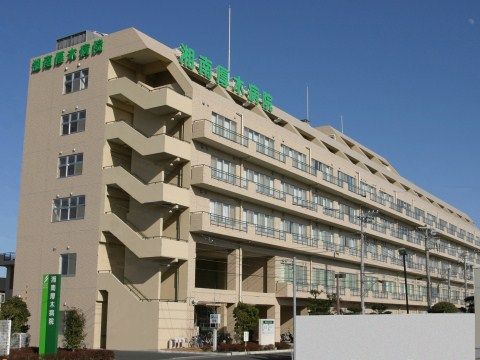 手前側に階段があり、窓とベランダが並ぶ、６階建てで横に非常に長い大きなビル