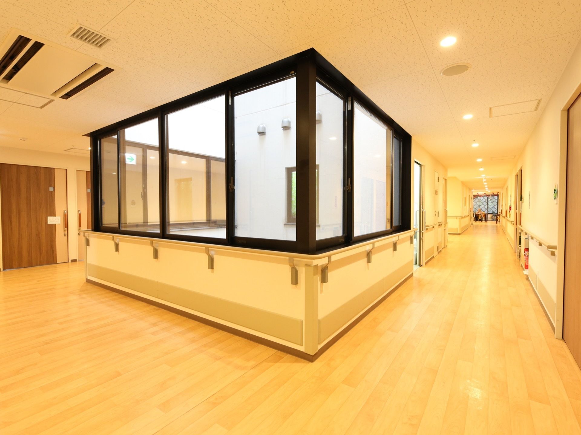 通路は、窓の外が吹き抜けになっていて、明るく開放感がある。両側の壁に手すりが設置され、角を曲がる際もつかみやすい。