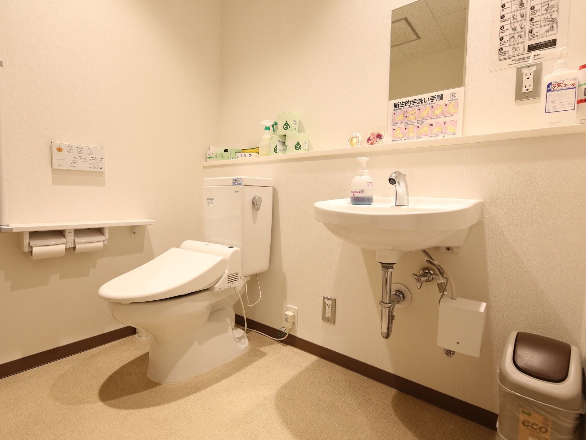 広い空間が設けられたトイレである。洗面台も設置されており、便利な自動水栓である。壁には、手洗いの手順が掲示されている。