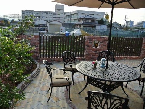 タイル張りの床にレンガの柵、花壇があるオープンカフェのようなテラス