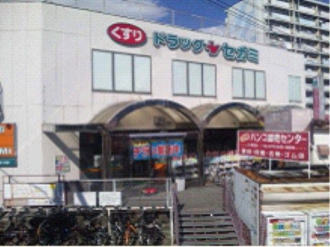 沢山の自転車が置かれた駐輪場と2階建てで外にも商品の並んだドラッグストア