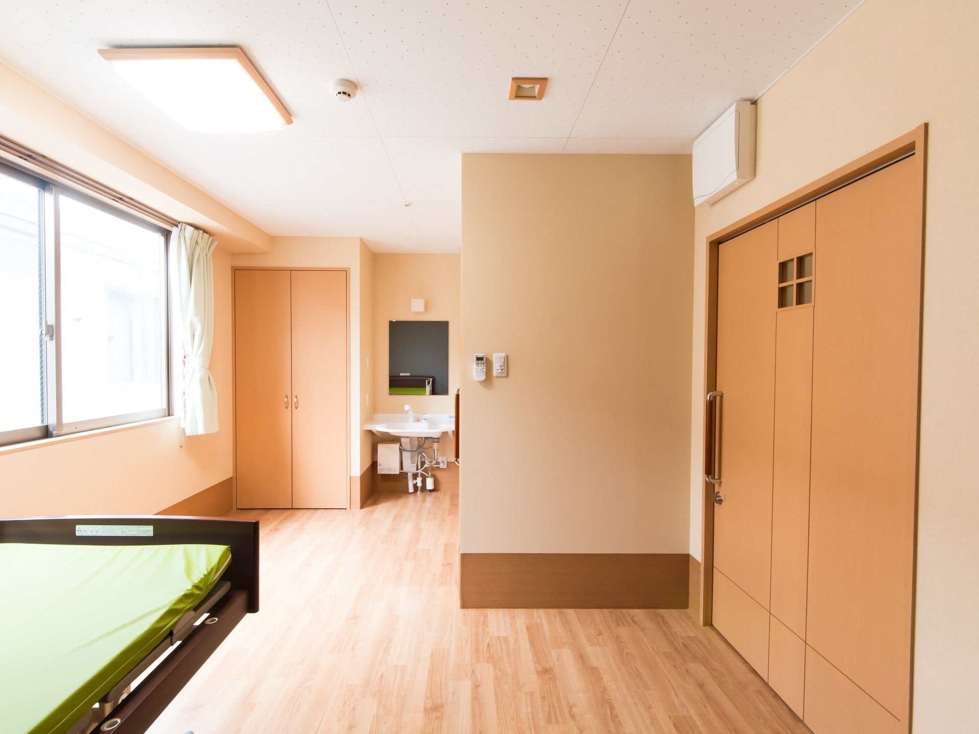 居室の床や壁はナチュラル系の色を基調としており、暖かみのある雰囲気である。収納スペースや洗面台が設置されている。