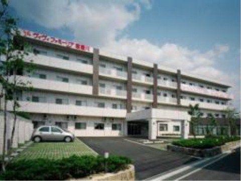 駐車場の奥にある、横に10室以上、地上４階建ての白っぽい施設