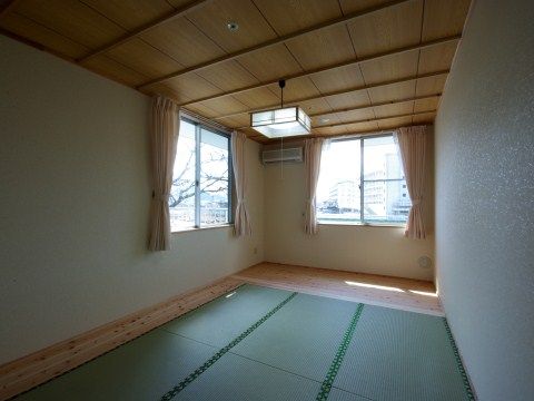 窓が2つの方向に設けられ、板の間がある白い壁の和室