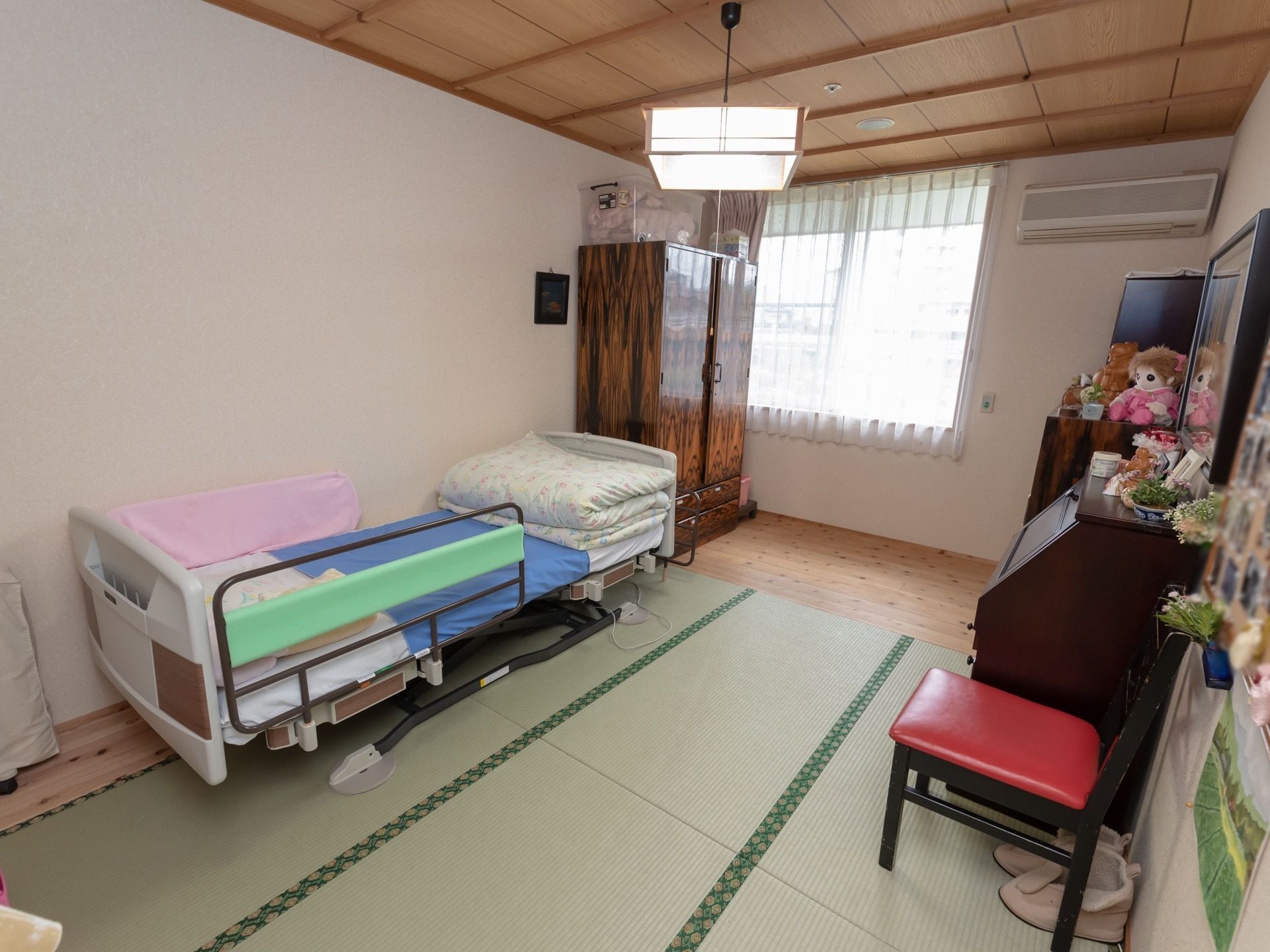 畳敷きの和室である。エアコン完備、ベッドや収納家具が設置されている。窓からは光が入り、室内は落ち着いた自然光が差し込む空間である。