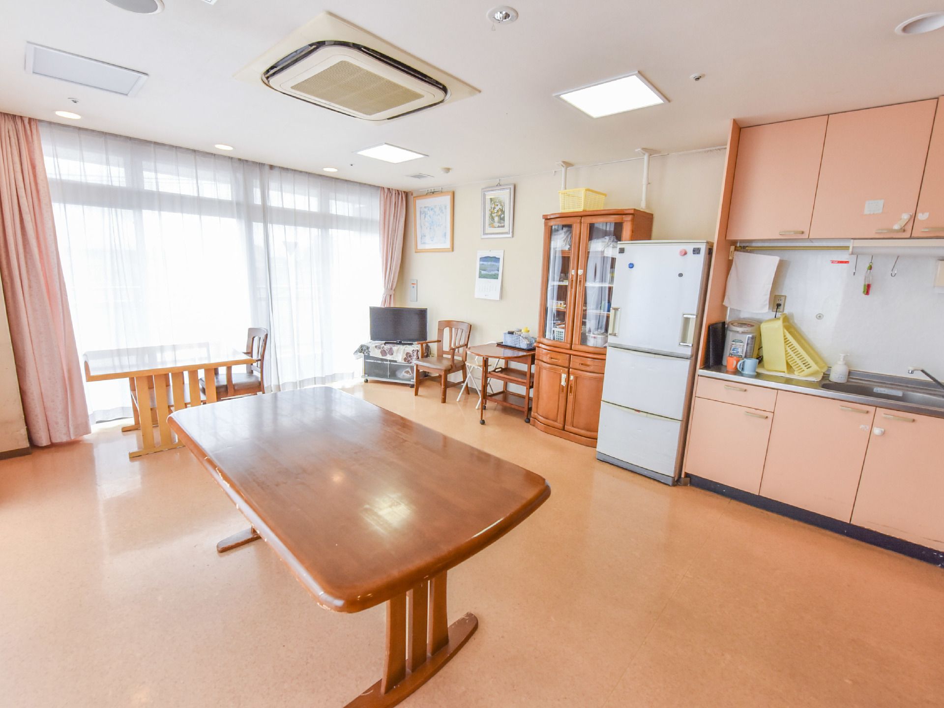 白色の壁に横一面はガラス戸になっている。壁際にはキッチン、冷蔵庫、食器棚、そしてテレビが置いてある。