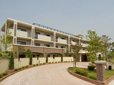 屋上付きの3階建て高齢者施設。建物前の道路には花壇がある。