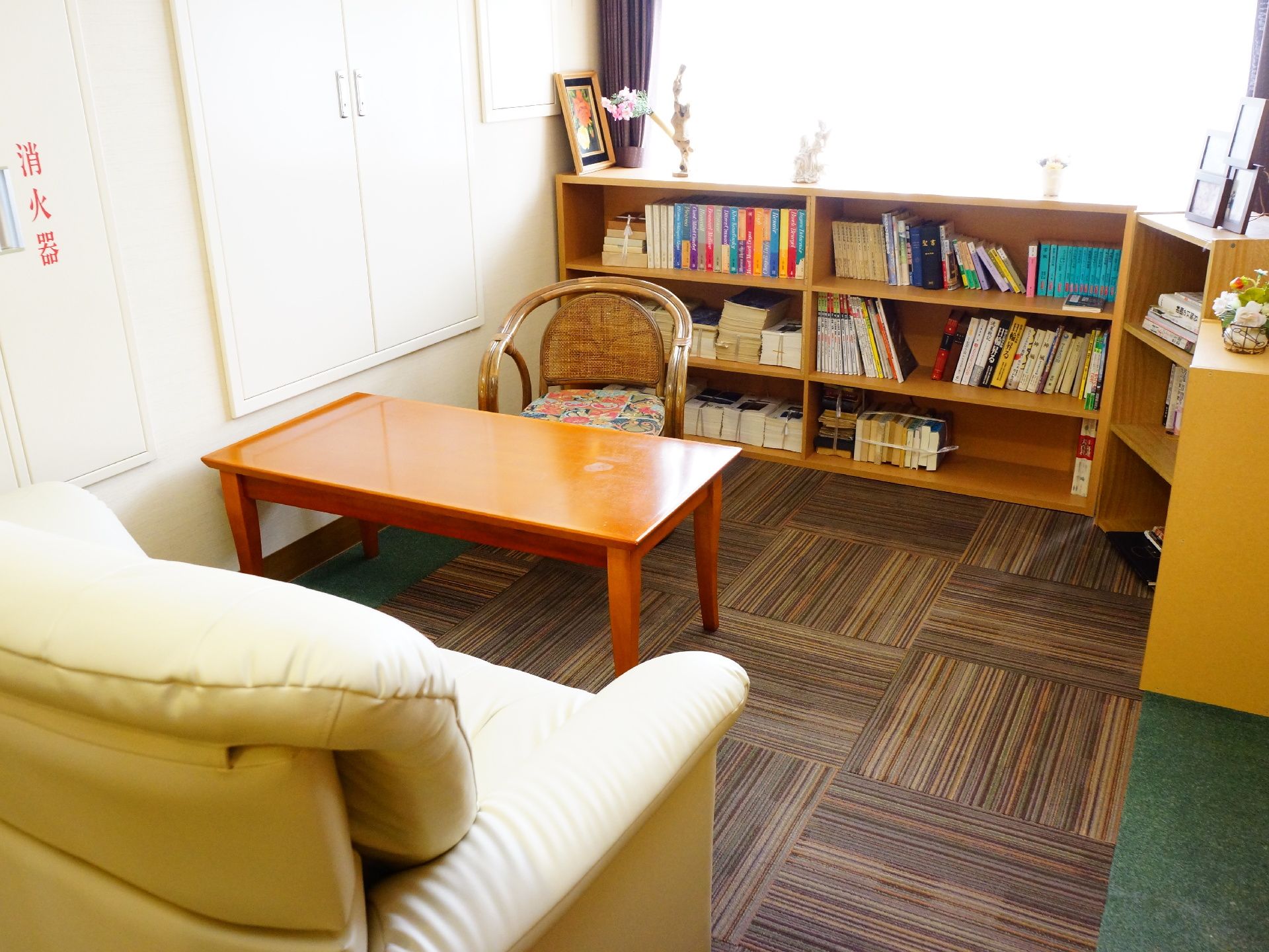 部屋にソファーや椅子、テーブルが設置されている。大きな窓の横には、横長の本棚が置かれている。中には多くの本が収納されている。