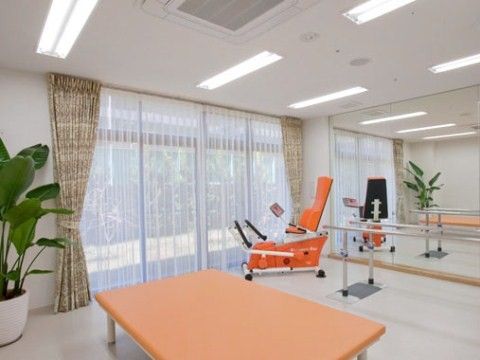 大きな窓の前に平行棒やトレーニング機器を設置したリハビリスペース