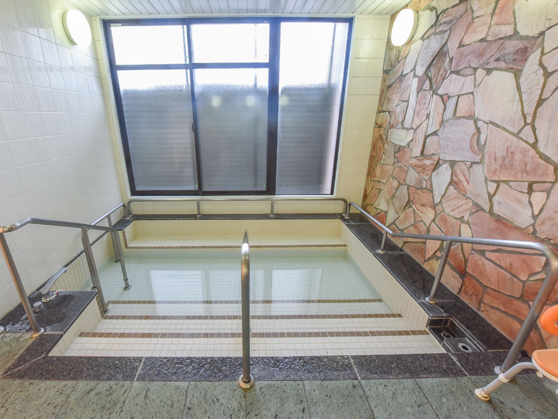 窓側に大きな浴槽がある。浴槽には手すりが取り付けられている。階段が設けられているので入浴時に足への負担が軽減できる。