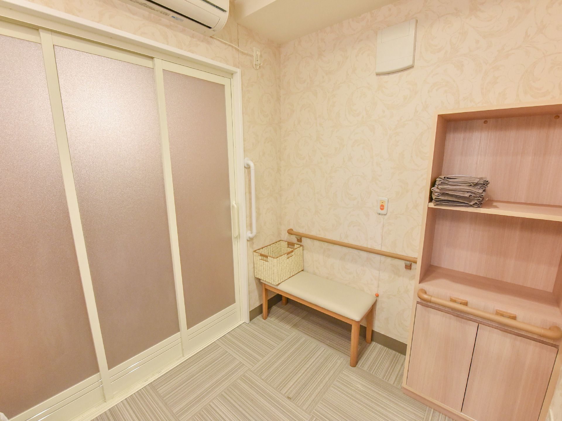 洗面所兼脱衣所になっている場所には木製の棚が置かれている。棚の上段には茶色いタオルが数枚収納されている。