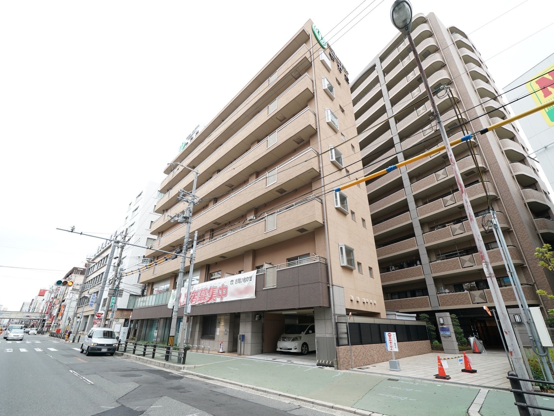 施設はベージュ色の外壁の７階建てで、マンションのような外観である。１階部分に駐車スペースが設けられている。