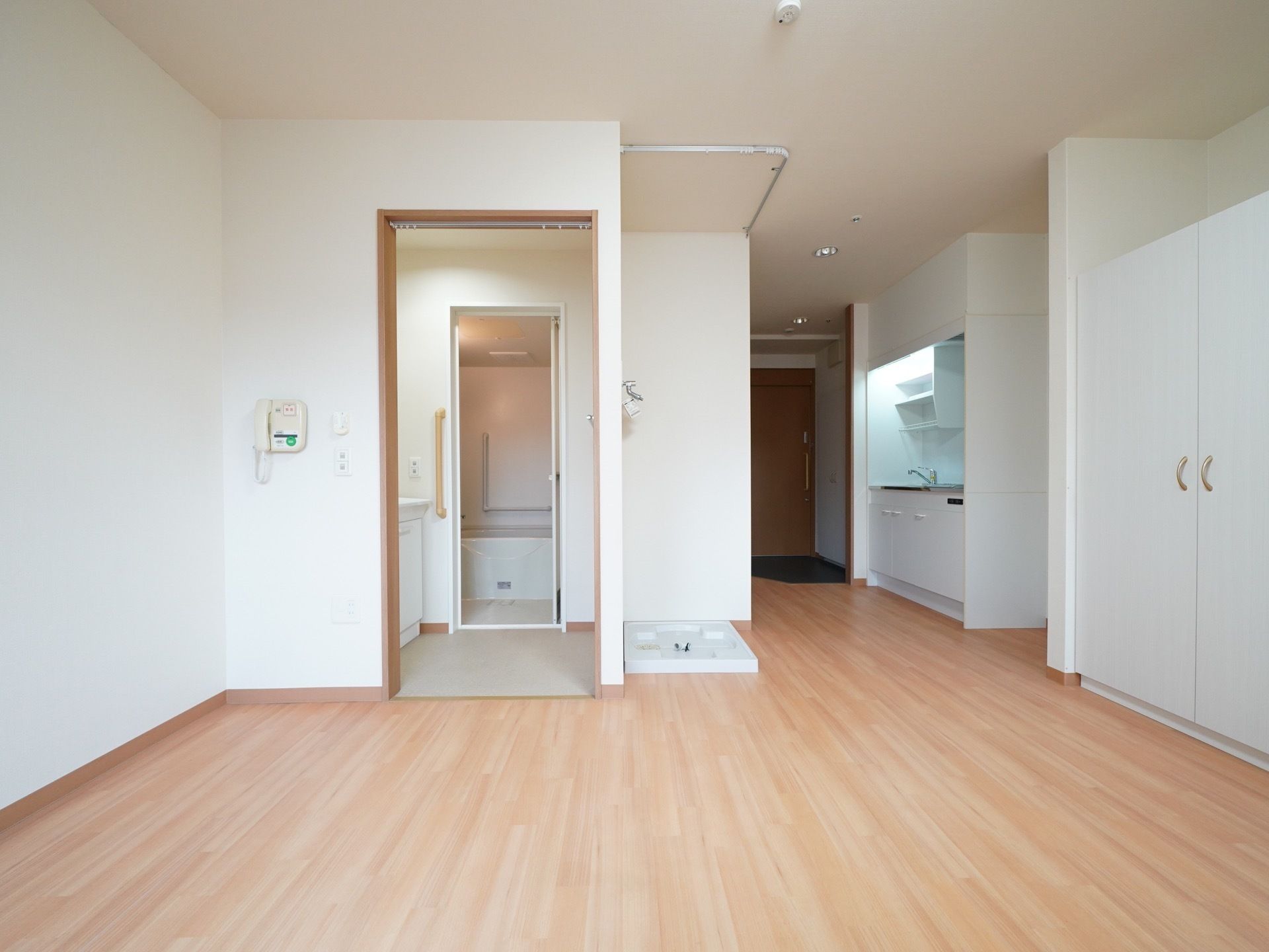 居室には白色の大きな扉のクローゼットがある。両開きなので荷物の出し入れがしやすい。キッチンも設置されている。