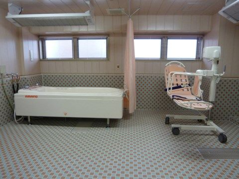 寝たまま吊り下げられた形で浴槽に入るための機械がある浴室