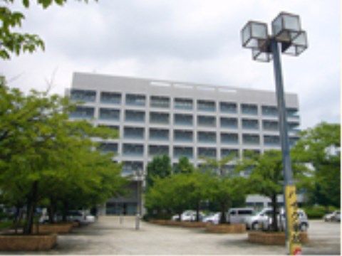 正面の窓と外壁が格子状に見えるデザインが目を引く建物である。正面には駐車場が整備され、木が植えられている。
