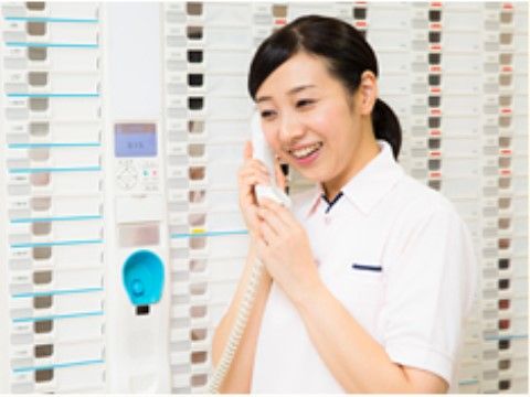 緊急通報通話装置の受話器を手に、笑顔で応対している女性スタッフ