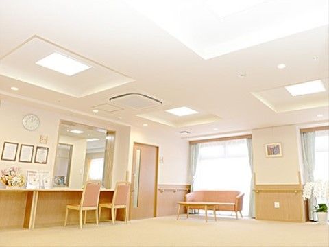 広々とした明るいエントランスである。受付があり、そばには椅子が完備されている。壁には安全のための手すりが設置されている。