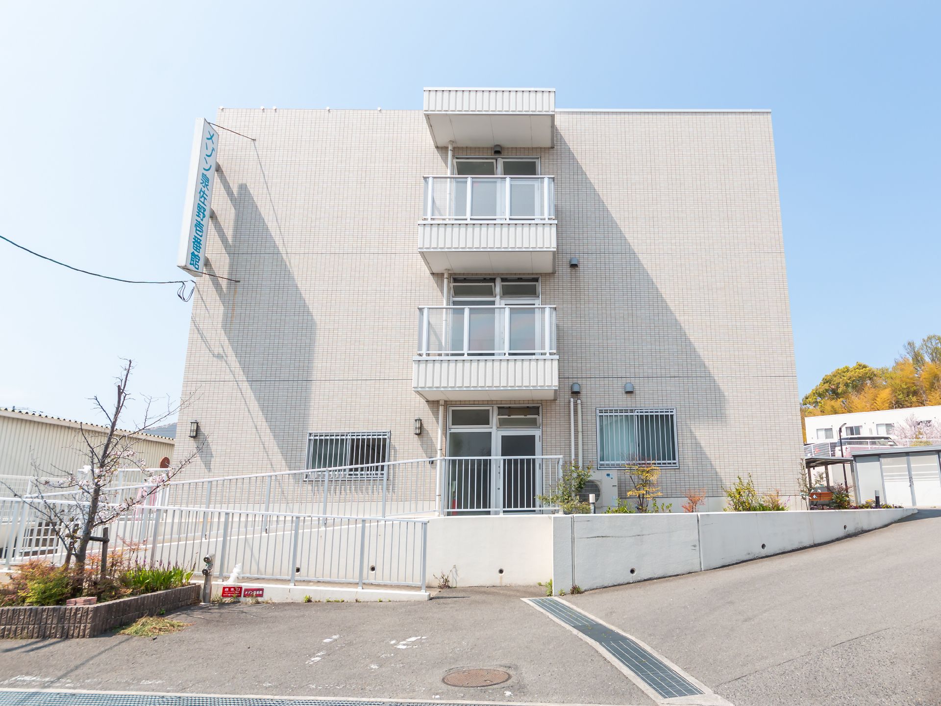 同じような窓が並ぶ、3階建てで白っぽい施設の玄関側