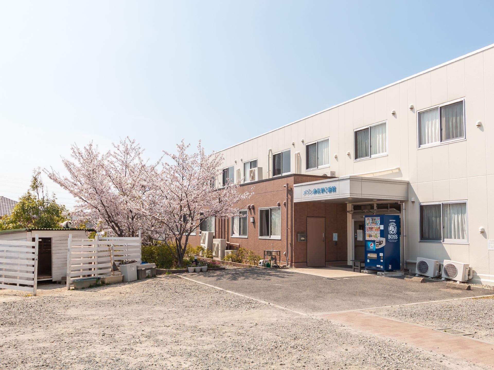 外観が白く、施設名が青字で表示された２階建ての建物の玄関周り