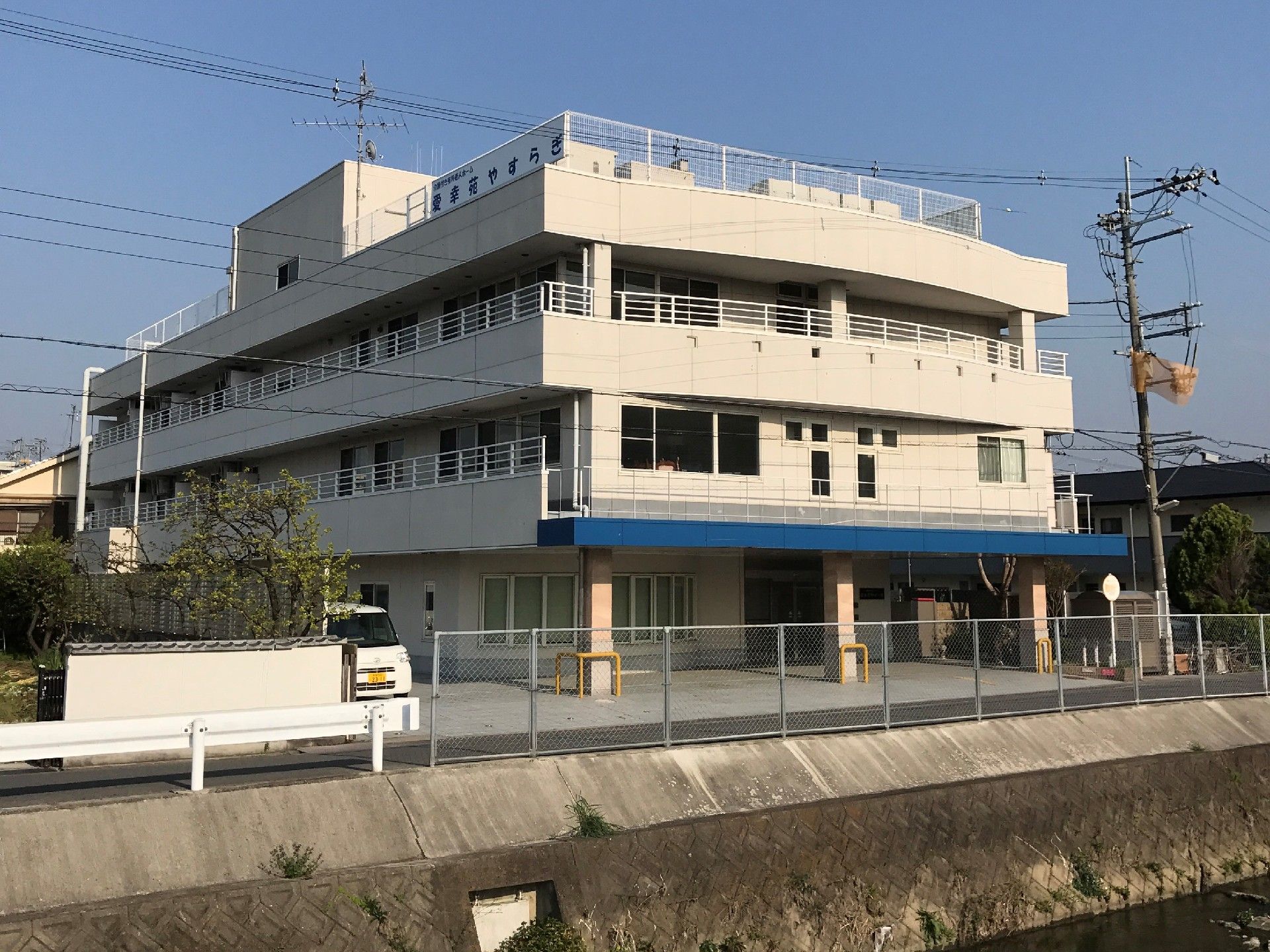 川沿いにある、外壁の一か所に入った青いラインが特徴的な建物