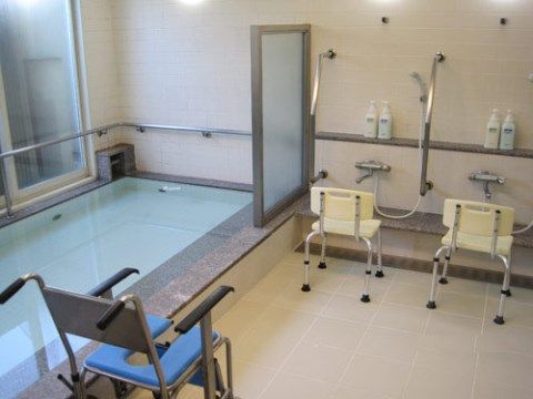窓際に大きな浴槽がある。浴槽の周囲には手すりが付き、２つのシャワー台と浴槽の間はパーテーションで仕切られている。
