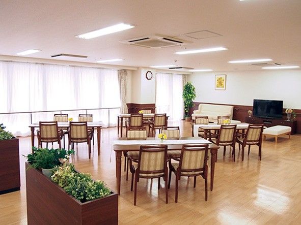 テーブルと椅子が整然と配置されている。洗面台が2台設置されている。壁には手すりがある。厨房が隣接されている。