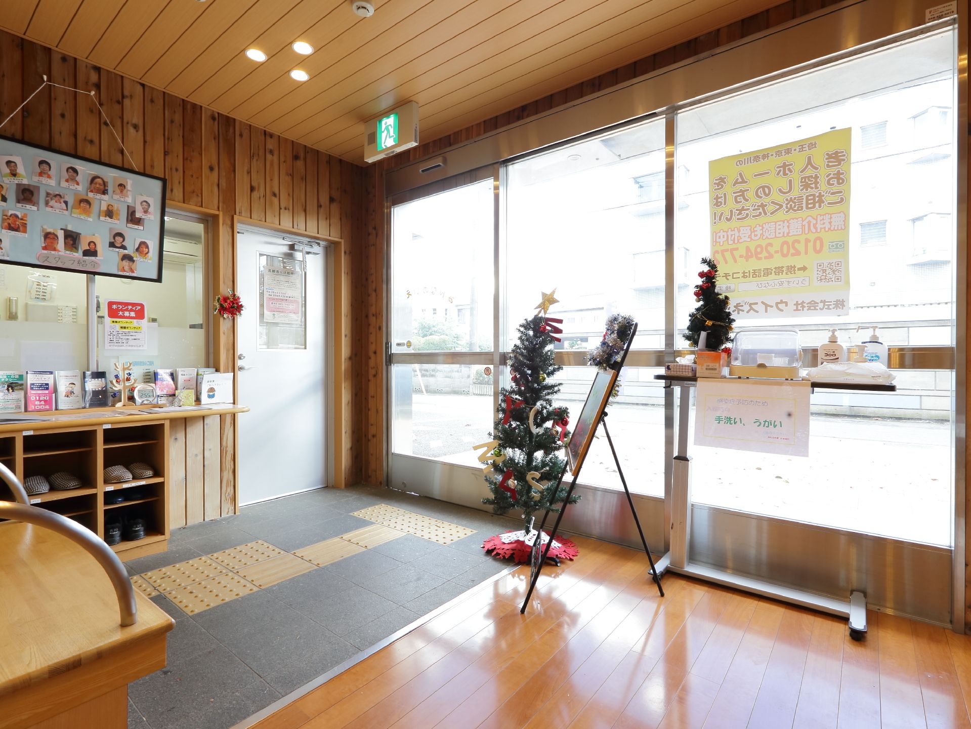 施設の入り口は自動ドアになっている。室内は屋外との段差の少ない造りになっている。スタッフの顔写真が貼られている。